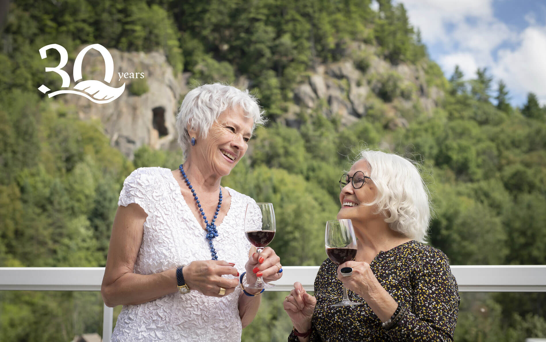 Senior citizens enjoying good wine and good food on the outdoor terrace at their retirement home in Saint-Sauveur